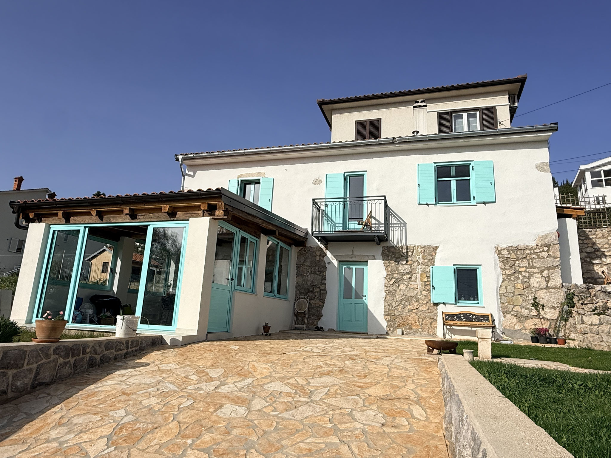 Anahata Space von außen — weißes Haus mit türkisen Fensterläden